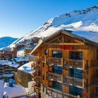 a hotel with a snow covered mountain in the background at Langley Hôtel Tango, Val Thorens