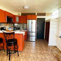a kitchen with orange cabinets and a bar with stools at Cozy apartment with pkg and laundry. Pet friendly, Ponce