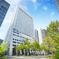 a tall white building in a city with trees at Hotel Nikko Osaka