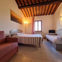 a room with two beds and a couch and a tv at Hotel Da Graziano, San Gimignano