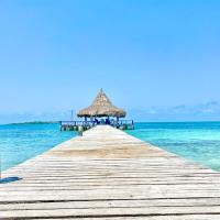 a wooden pier with a straw umbrella and the ocean at Hotel Tintipan, Tintipan Island