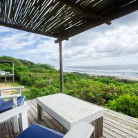 a table and chairs on a deck with a view of the ocean at Baleia Azul 11, Ponta Mamoli