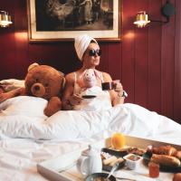 a woman sitting in bed with a teddy bear and a teddy bear at Naâd Hotel Sarlat Centre Ville, Sarlat-la-Canéda