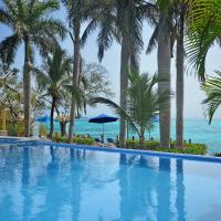 a swimming pool with palm trees and the ocean at Hotel La Joya Isla Mujeres