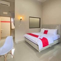 a bedroom with a white bed and a desk and a chair at RedDoorz Syariah near Hajimena Lampung