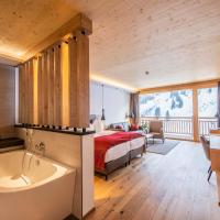 a bedroom with a bed and a tub in a room at Damülser Hof - Wellness & Spa, Damuls