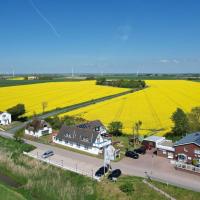 an aerial view of a town with a yellow rapeseed field at Hotel-Restaurant England, Nordstrand
