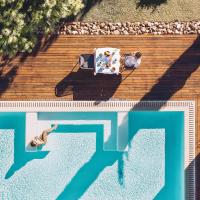 a man sitting in a chair next to a swimming pool at Las Gaviotas Suites Hotel & Spa, Playa de Muro