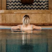 a woman sitting in the water in a swimming pool at Hotel Le Médina Essaouira Thalassa sea & spa – Mgallery