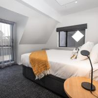 a bedroom with a bed and a table with a lamp at Hotel Give, Christchurch