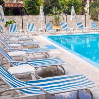 a row of lounge chairs next to a swimming pool at San Remo Hotel, Larnaca