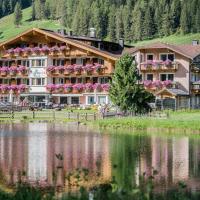 a large building with flowers on it next to a lake at Hotel Waldheim, Sesto