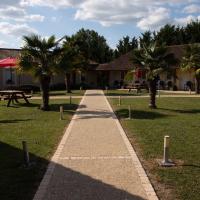 a path in a park with palm trees and picnic tables at Rev'hotel, Ribérac