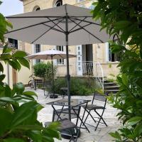 a table and chairs with an umbrella in front of a building at Le Rodin Bazas