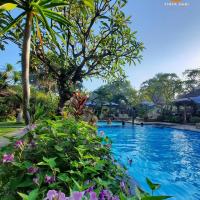 a swimming pool at a resort with purple flowers at Tirta Sari Bungalow, Pemuteran