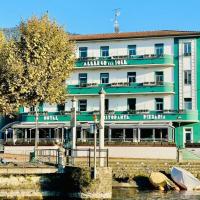 a large green and white building next to a river at Albergo Del Sole, Porto Valtravaglia