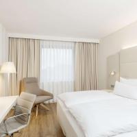 a hotel room with a large white bed and a desk at NH Düsseldorf City Nord