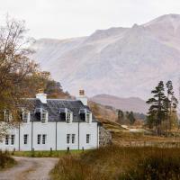 a white house on a dirt road with mountains in the background at Coulin Farmhouse, Kinlochewe