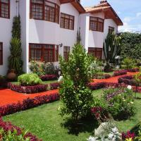 a garden in front of a building with flowers at Hotel & Bungalows Villa Valencia, Huaraz