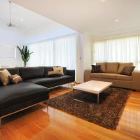 a living room with a black leather couch and a table at Pinnacle Apartments, Hamilton Island