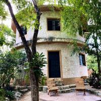 a building with two chairs in front of it at La Casa Redonda. Tulum-Cobá, Francisco Uh May
