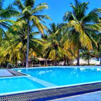 a swimming pool with palm trees in the background at Pearl Oceanic Resort - Trincomalee