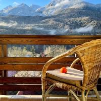 a wicker chair on a deck with a view of mountains at Apart 64 Guest House, Krasnaya Polyana