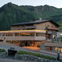 a large building with a mountain in the background at Alpenresort Walsertal, Damuls