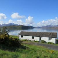 a white house with a lake in the background at Spectacular Highland Cottage Overlooking the Sea, Tongue