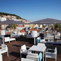 a restaurant with white chairs and tables and umbrellas at Hotel Mundial, Lisbon