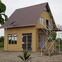 a yellow house with a metal roof and a staircase at Usambara Estates, Bagamoyo