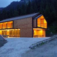a brick house with large windows on a hill at Vallesinella Hotel Restaurant Bar, Madonna di Campiglio
