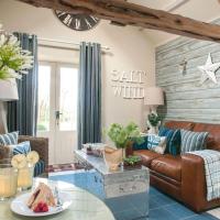 a living room with a leather couch and a table at Saltwind Granary, Hartland