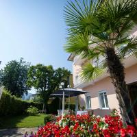 a palm tree in front of a house with flowers at Villa Auguste, Pörtschach am Wörthersee