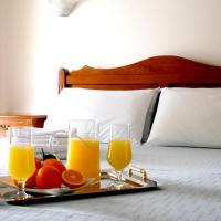 a tray with two glasses of orange juice and fruit on a bed at Zouzoulas Filoxenia - Koralia Apartments, Milina