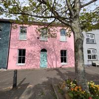 a pink building with a tree in front of it at Unique Townhouse with Large Garden down to the Sea, Killough