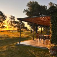 a wooden deck with a table and chairs in a field at Zorzal Casa de Campo, Colonia del Sacramento
