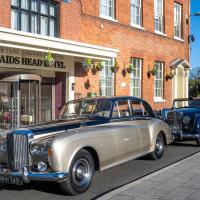 two old cars parked in front of a building at The Maids Head Hotel, Norwich