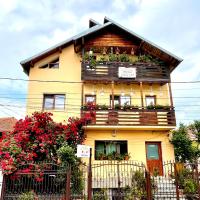 a yellow house with flower boxes on the windows at Pensiunea Cristiana, Curtea de Argeş