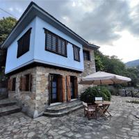 a house with a table and an umbrella at Cozy Blue Stone House with a Great Sea View., Tsagarada