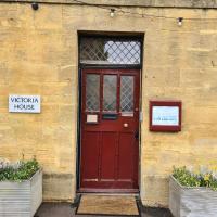 a red door on the side of a building with two plants at Victoria House, Stow on the Wold