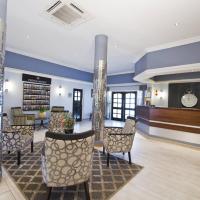 a lobby with a waiting area with chairs and tables at Hotel Thuringerhof, Windhoek