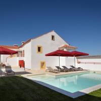 a villa with a swimming pool with red umbrellas at Casa Lidador - Obidos, Óbidos