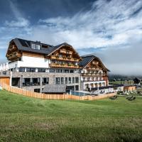 a large building on top of a green field at ALMGUT - Mountain Wellness Hotel, Sankt Margarethen im Lungau