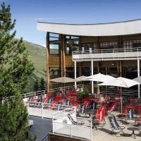 a deck with red chairs and tables on a building at Belambra Clubs Les Menuires - Neige Et Ciel