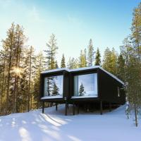 a black house in the woods in the snow at Arctic TreeHouse Hotel, Rovaniemi