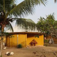 a yellow house with palm trees in front of it at Rundbungalow auf Lionsrest, Grand-Bassam