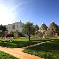 a building with a grass yard with trees and a path at Masseria Cervarolo, Ostuni