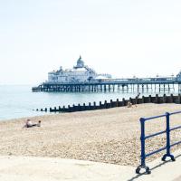 a beach with a pier and people laying on the sand at Shore View Hotel, Eastbourne