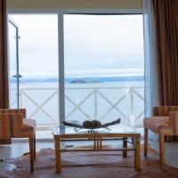 a living room with two chairs and a table and a large window at Hotel Las Dunas, El Calafate